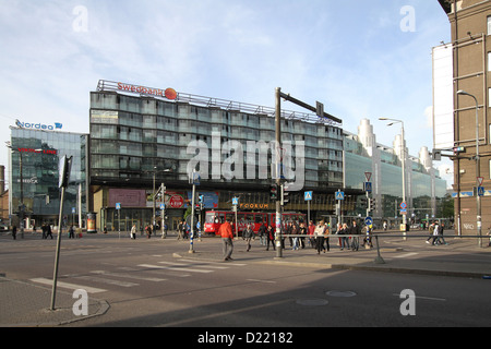 Swedbank and modern buildings at a busy pedestrian crossing in Narva Mantee Tallinn, with people crossing the street at traffic lights and signals.. Stock Photo