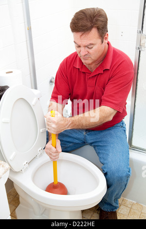 Man using a plunger to unclog the toilet.  Stock Photo