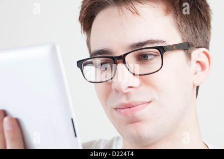 Young male wearing glasses looking at the screen of his laptop or digital tablet. Close up. Stock Photo