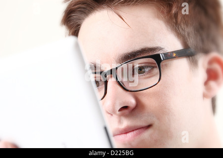 Young male wearing glasses looking at the screen of his laptop or digital tablet. Close up on eyes. Stock Photo
