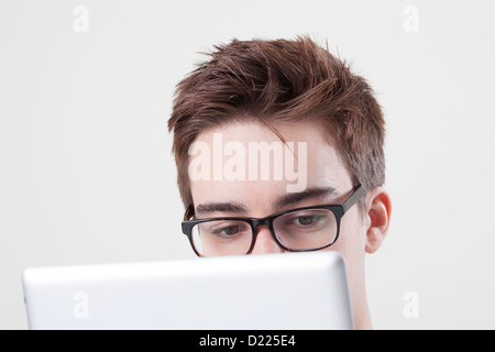 Young male wearing glasses looking at the screen of his laptop or digital tablet. Close up on eyes. Stock Photo