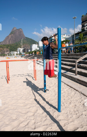 A man doing his morning pull-up exercises at the open air gym on Ipanema beach Stock Photo