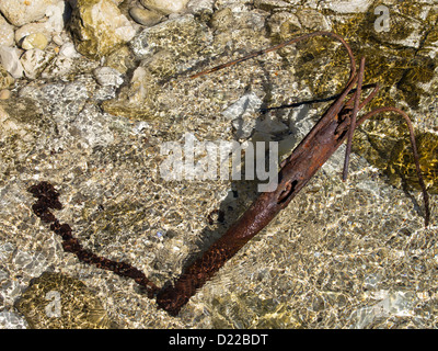 old rusty anchor on the rocky coast Stock Photo
