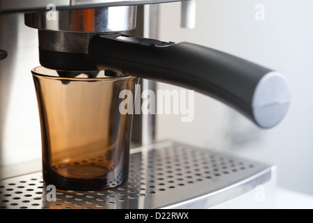 Empty dark glass cup in espresso coffee machine Stock Photo