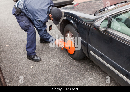 Parking enforcement officer installing a wheel lock on a car - Washington, DC USA Stock Photo