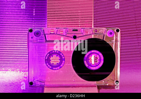 Transparent Cassette tape. Pink and blue background. Stock Photo