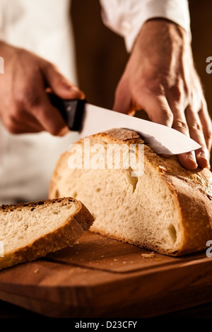 Baker Slicing Bran Bread on a Cutting Board Stock Photo