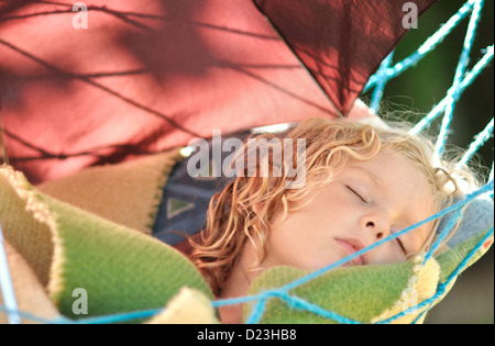 Child sleeps in a hammock in the garden. Stock Photo