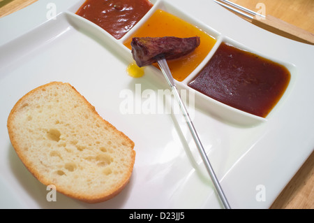 Place setting, Fondue plate with different sauces, bread and meat skewer Stock Photo