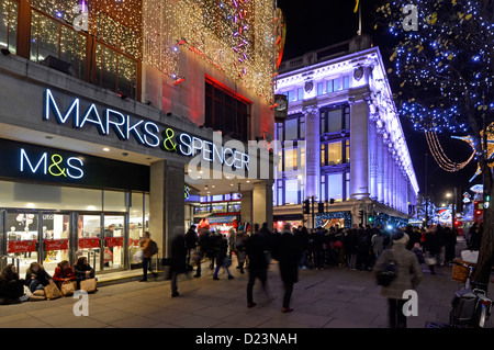 Christmas decorations with Xmas lights Marks and Spencer Oxford Street West End M&S retail business store shopping in London at night Selfridges UK Stock Photo