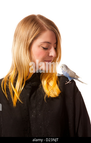 Friendly parakeet sitting on a womans shoulder. She is looking down on the bird. Stock Photo