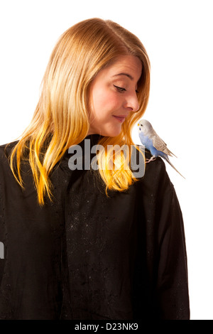 Friendly parakeet sitting on a womans shoulder. She is looking down on the bird. Stock Photo