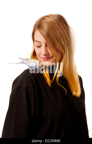 Friendly parakeet sitting on a womans shoulder. She is looking down on the bird. Stock Photo