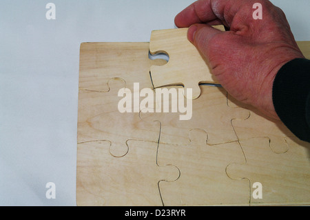 Pieces of jigsaw puzzle being put together on a table Stock Photo