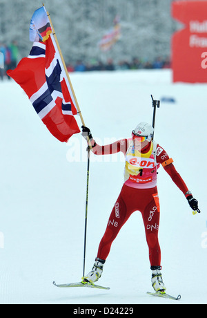 Biathlete Tora Berger (R) from Norway carries a flag and wins the women's 12.5 km mass start race of the Biathlon World Cup at Chiemgau Arena in Ruhpolding, Germany, 13 January 2013. Photo: Andreas Gebert Stock Photo