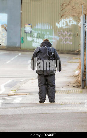 Belfast, Northern Ireland, UK. 14th January 2013.   ATO from the RLC EOD 11th Squadron (The Bomb Squad) wearing most of his bomb proof suit, examines the scene around a suspect device before advancing to defuse it. Stock Photo