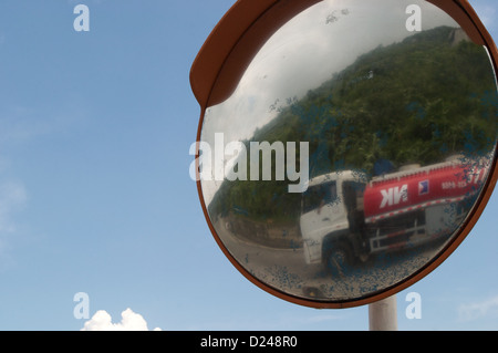 A petrol tanker seen through the reflection of a road mirror makes its way up the Hai Van Pass, Vietnam Stock Photo