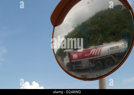 A petrol tanker seen through the reflection of a road mirror makes its way up the Hai Van Pass, Vietnam Stock Photo