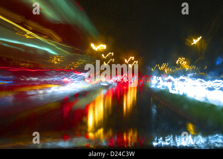Driving in traffic on a wet dark evening seen through a rain-soaked windscreen. Stock Photo