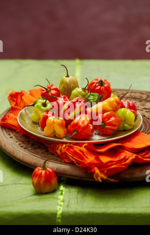 A plate of Scotch bonnet peppers on a carved wooden board Stock Photo