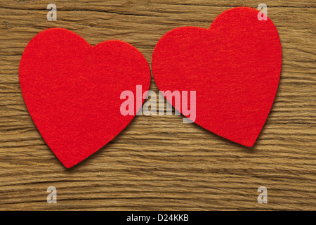 Two large red hearts of felt on old brown wooden board Stock Photo