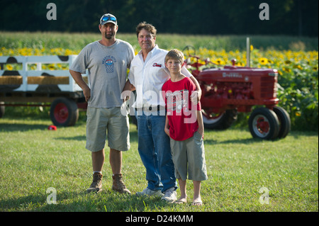 Farm family standing in front of corn crop growing Stock Photo