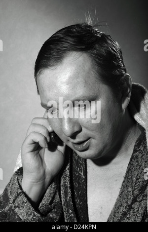 young man in a bathrobe talking on a cell phone Stock Photo