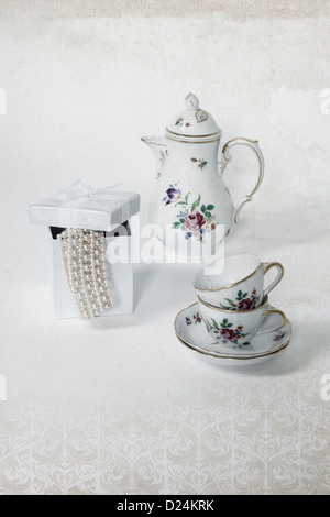 two vintage coffee cups, a coffee pot and a present box with a pearl necklace Stock Photo