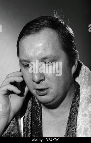 young man in a bathrobe talking on a cell phone Stock Photo