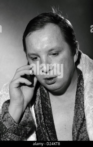 young man in a bathrobe talking on a cell phone Stock Photo