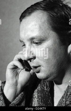 young man in a bathrobe talking on a cell phone Stock Photo