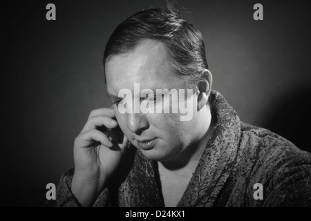 young man in a bathrobe talking on a cell phone Stock Photo