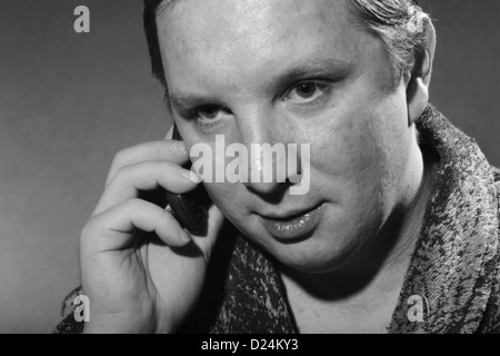 young man in a bathrobe talking on a cell phone Stock Photo