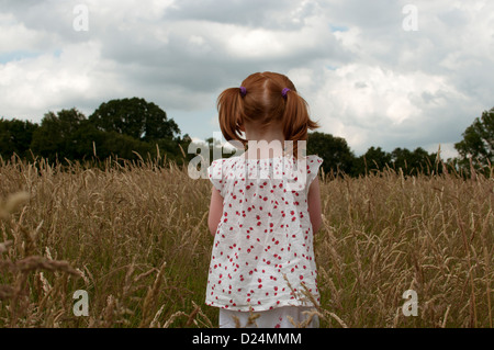 A little girl standing in a field, rear view Stock Photo