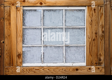 Horizontal image of an old wooden nine-lite window pane in a wooden wall, covered in ice crystals. Stock Photo