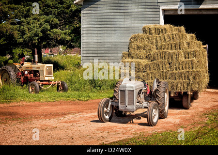 Vintage tractor hauling a wagon load of hay bales. Stock Photo