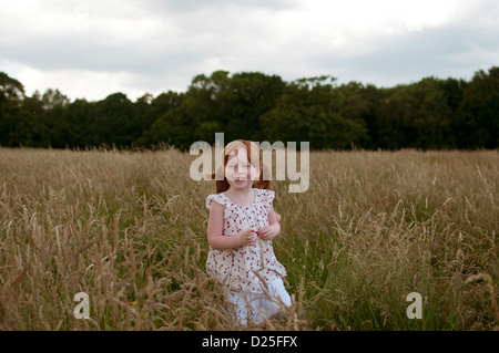 A little girl standing in a field, laughing Stock Photo