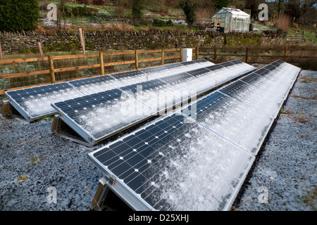 Snow frost on free standing solar panels panel and greenhouse in winter January garden on smallholding in West Wales, UK   KATHY DEWITT Stock Photo