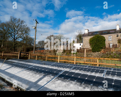 Snow frost on free standing solar panels panel and stone house home cottage barn buildings in winter on smallholding in West Wales, UK   KATHY DEWITT Stock Photo