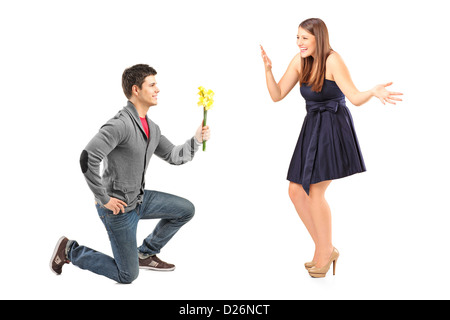 A male kneeling with flowers and his excited girlfriend isolated on white background Stock Photo