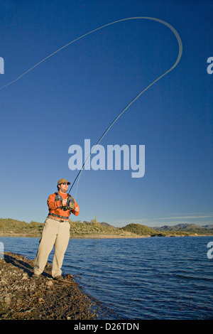 Man casts his fly fishing line into Lake Pleasant in Arizona Stock Photo