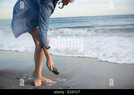 USA, New York State, Rockaway Beach, Woman collecting seashells on beach Stock Photo