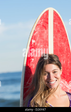 USA, New York State, Rockaway Beach, Portrait of woman with surfboard Stock Photo