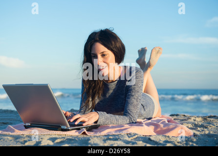 USA, New York State, Rockaway Beach, Woman using laptop on beach Stock Photo
