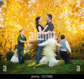 USA, Utah, Bountiful, Family with children (2-3, 4-5, 6-7, 8-9) dancing in garden at autumn Stock Photo