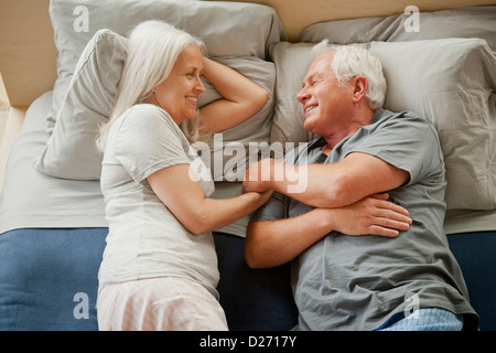 Senior couple laying on bed and laughing Stock Photo