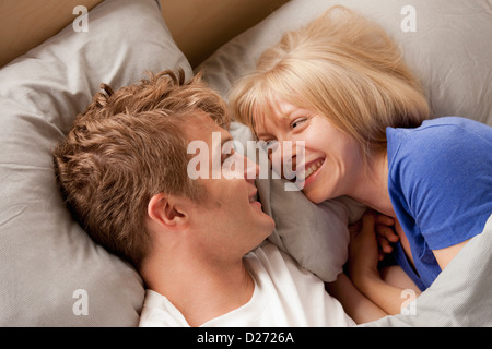 Elevated view of laughing couple lying in bed Stock Photo