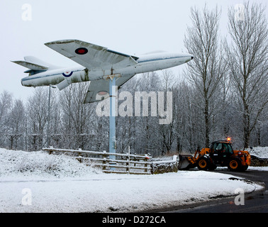 Snow being cleared by the side of a Hawker Hunter jet mounted on a pole at Ford West Sussex UK Stock Photo