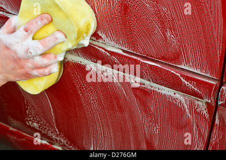 Washing the car by hand with a yellow soapy sponge better than automated car wash Stock Photo