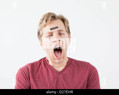 Yawning man with sticker on his forehead Stock Photo
